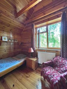 a log cabin bedroom with a bed and a window at Anika dom w lesie nad jeziorem Słupinko in Dziemiany