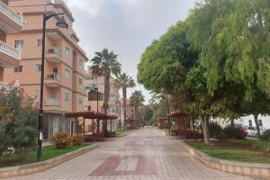 an empty street in a city with palm trees and buildings at Seaside apartment with balcony in Las Galletas