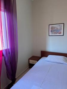 a bedroom with a bed and a window with purple curtains at Joanna Apartment in Yerakiní