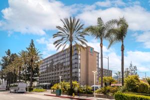 a building with palm trees in front of a street at Clarion Hotel Anaheim Resort in Anaheim