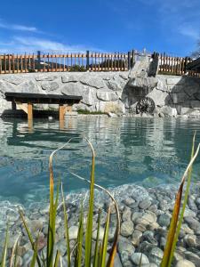 a pool of water with a picnic table and rocks at das brunn - Luxus Chalet in Kirchberg in Tirol