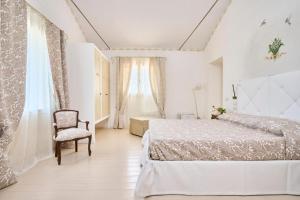 Agriturismo Borgonuovo في ريميني: غرفة نوم بيضاء بسرير وكرسي