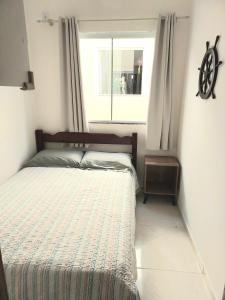 1 cama en un dormitorio con ventana en Apartamento novo 450 mt da praia Ingleses, en Florianópolis