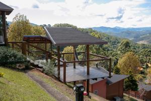 una terraza de madera con techo sobre una colina en Pousada Varanda das Colinas, en Monte Verde