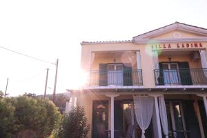 a large white building with a balcony and the sun at Villa Ladina in Lygia