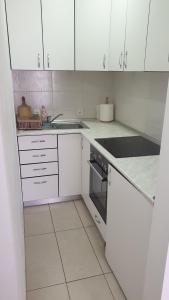 a white kitchen with white cabinets and a sink at Apartman Borko 2-1 in Loznica