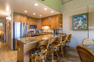 eine Küche mit einer Bar mit Stühlen und einem Kühlschrank in der Unterkunft Papakea E407 in Kahana + 21 Fotos