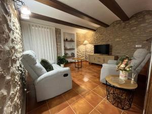 ein Wohnzimmer mit 2 weißen Stühlen und einem TV in der Unterkunft Ca la Beata in Cálig