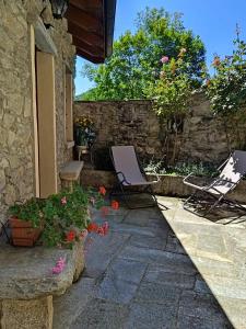 eine Terrasse mit zwei Gartenstühlen und Blumen vor einem Gebäude in der Unterkunft Casa Elisa affittacamere in Armeno