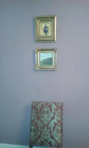 dwa oprawione zdjęcia na niebieskiej ścianie z krzesłem w obiekcie Chambre d'hôte, 3 pièces 90m2 w mieście Autun