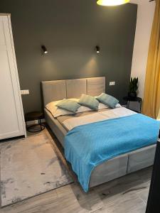 1 dormitorio con 1 cama grande con manta azul en Pokoje I Apartamenty Polna 19, en Niechorze
