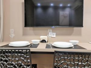 a table with plates and wine glasses and a tv at Studio em Pinheiros SP in Sao Paulo