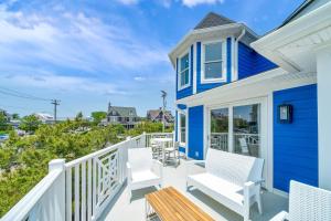 a blue and white house with white chairs on a balcony at Mahalo Cape May Townhomes in Cape May