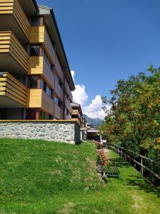a building with a retaining wall next to a green yard at Appartamento I Larici in Folgarida