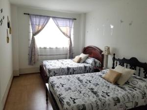 1 Schlafzimmer mit 2 Betten und einem Fenster in der Unterkunft VISTA ÚNICA HERMOSO Mini Departamento en Ambato in Ambato