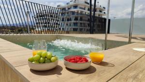 un bol de fruta y dos vasos de zumo en una mesa en ALLONBAY sea front luxury penthouse, en Villajoyosa