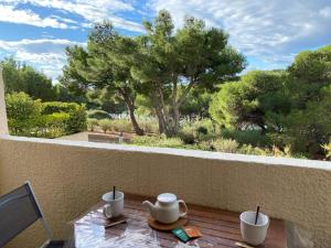 uma mesa com um conjunto de chá numa varanda com vista para as árvores em Studio cosy à saint-Pierre la mer em Fleury