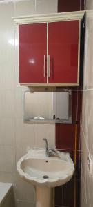 ein Waschbecken mit einem roten Schrank darüber in der Unterkunft العجمى الكيلو 21 شاطئ النخيل in Alexandria