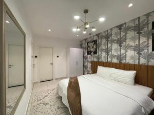 - une chambre avec un lit et un mur orné de palmiers dans l'établissement Embassy Gardens Apartments, à Cantonments