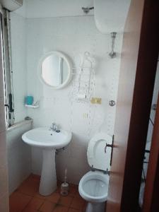 een badkamer met een wastafel, een toilet en een spiegel bij La Casa dell'Artista in Marconia
