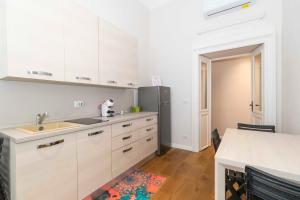 uma cozinha com armários brancos e um frigorífico de aço inoxidável em Piccolo Principe em Turim