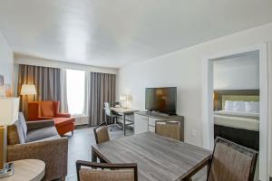 ニューオーリンズにあるCountry Inn & Suites by Radisson, New Orleans I-10 East, LAのベッド、テーブル、椅子が備わるホテルルームです。