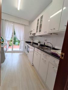 a kitchen with white cabinets and a wooden floor at Apartamento con jardin privado junto playa Usil - Mogro in Miengo