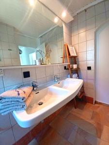 ein Badezimmer mit einem großen weißen Waschbecken und einem Spiegel in der Unterkunft Ferienwohnung Lucia in Schiefling am See