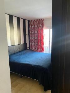 1 dormitorio con cama azul y cortina roja en Apartamento familiar, en Torroella de Montgrí