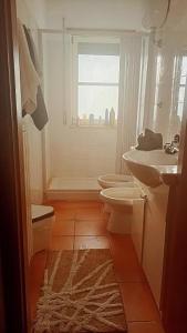 een badkamer met een wastafel, een toilet en een raam bij La Casa dell'Artista in Marconia