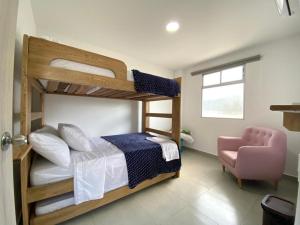 1 Schlafzimmer mit 2 Etagenbetten und einem rosa Stuhl in der Unterkunft NAHIR apartamento de playa en condominio Palmar del viento in San Bernardo del Viento