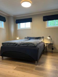 a bedroom with a bed in a room with two windows at Gårdsopphold Notodden in Notodden