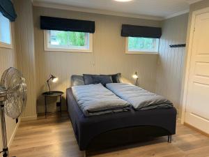a bed in a bedroom with two windows and a fan at Gårdsopphold Notodden in Notodden