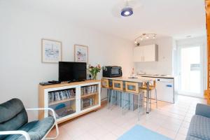 uma sala de estar com uma cozinha e uma mesa com uma televisão em Charmante maison à nbne plage em Narbona