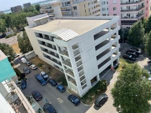 a large white building with cars parked in a parking lot at Apartament Summerland Crazy Beach Mamaia in Mamaia