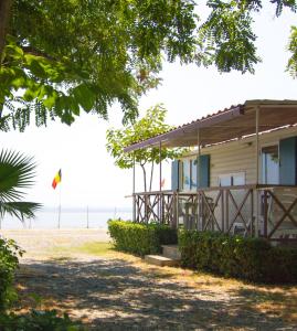 una casa sulla spiaggia con un aquilone in lontananza di Camping La Focetta Sicula a SantʼAlessio Siculo