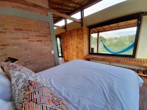 1 dormitorio con 1 cama y ventana con hamaca en Cabañas Finca La Buganvilia, en Sáchica