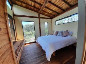 1 dormitorio con 1 cama en una habitación con ventanas en Cabañas Finca La Buganvilia, en Sáchica