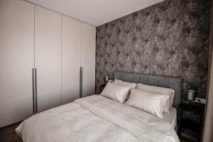 a bedroom with a large white bed with a wallpaper at Sodoben apartma v centru Ljubljane in Ljubljana