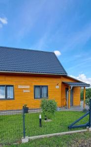 une maison orange avec une clôture devant elle dans l'établissement Słoneczne Wzgórze, à Lubrza