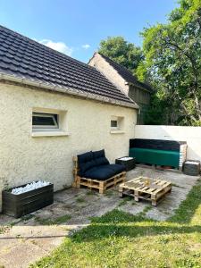 eine Terrasse mit Sofas und Tischen vor einem Haus in der Unterkunft Studio avec grand jardin + parking in Seraincourt
