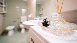a bathroom with a glass vase with a pine cone in it at Apartmani Gruzdovo in Delnice
