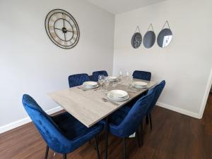 a dining room with a table and blue chairs at Kinetic Stays - Serenity Holiday Cottages in Sidmouth