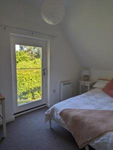 a bedroom with a bed and a large window at Myrtle Stables - converted, self-contained, countryside in Hernhill