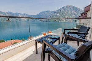 a balcony with two chairs and a table with wine glasses at Apartment 29 in Kotor
