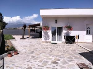 a white house with a stone patio in front of it at Country house Angela in Košute