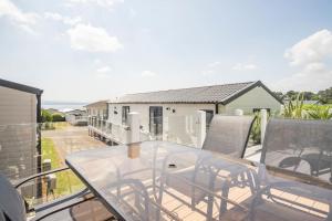 a balcony with a glass table and chairs at The Woodlark Lodge at Rockley Park in Lytchett Minster