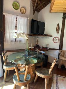 Habitación con mesa de cristal y 2 sillas. en Cabana Do Zuza, en Campos do Jordão