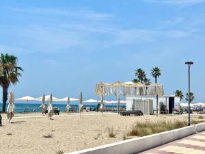 a beach with white umbrellas and the ocean at Golden Coast Calafell in El Vendrell
