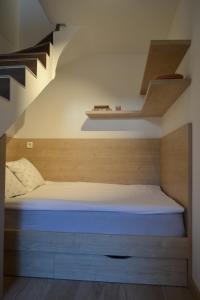 uma cama num pequeno quarto sob uma escada em APARTMA VODNIK em Bohinj
